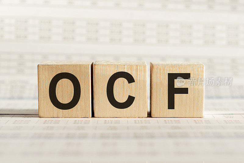 OCF -经营现金流量-首字母缩略词在木制立方体列的数字背景。